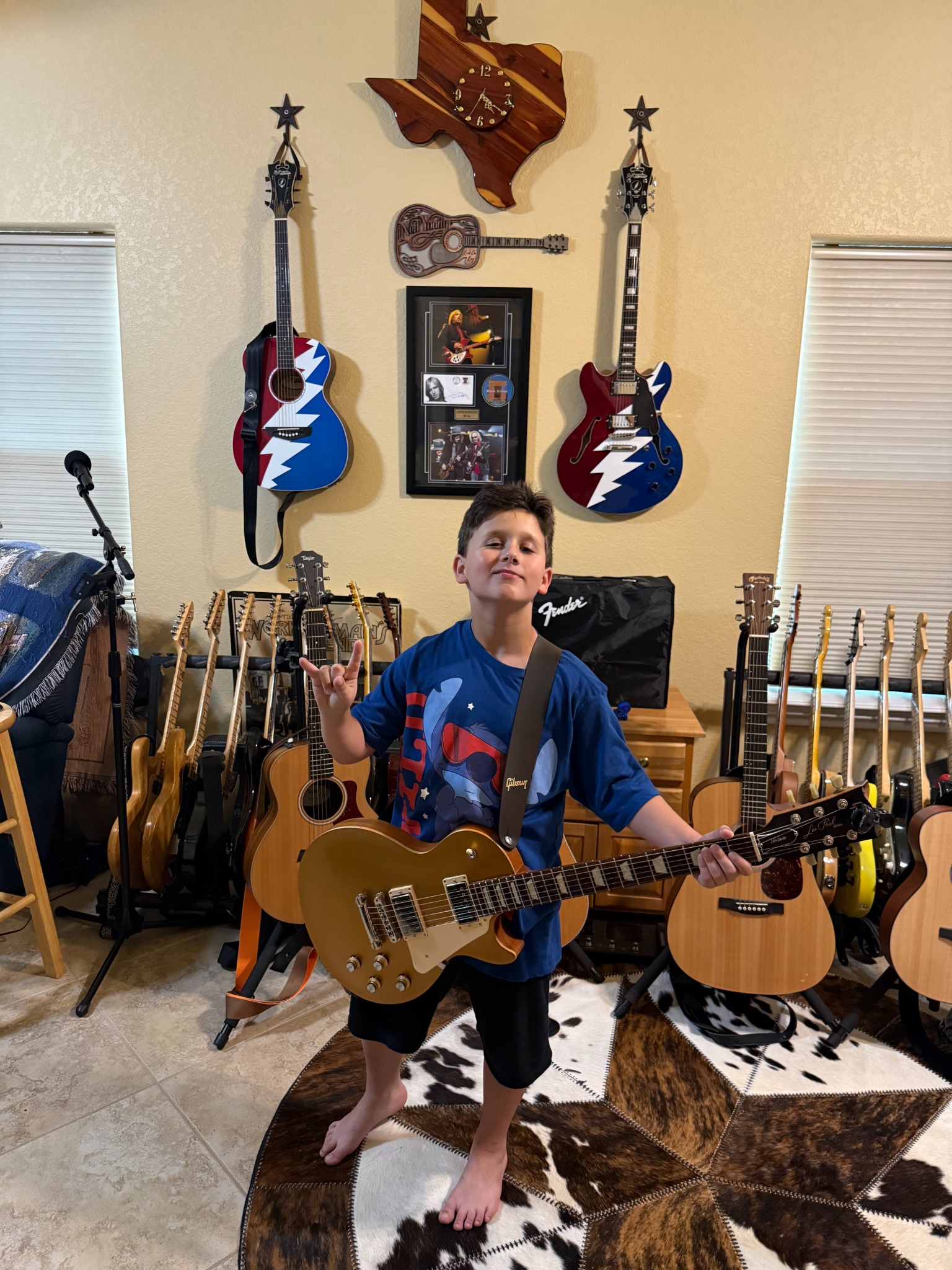 Jerrick playing an acoustic guitar in a room full of guitars